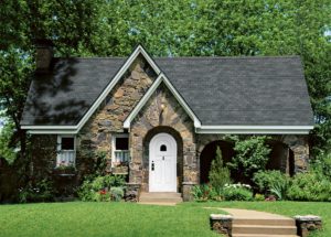 Home with green lawn, stone siding, and a grey asphalt shingle roof
