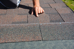 Roofing contractor pointing at asphalt roofing shingle