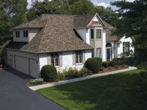 Suburban home with a green lawn, white siding, an brown asphalt shingle roofing